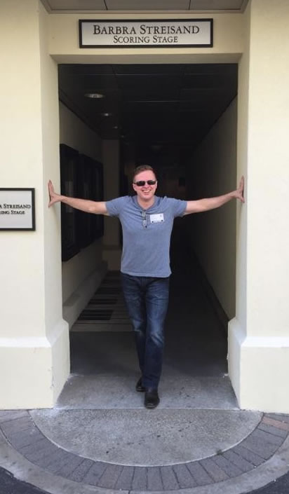 Stephen, wearing a blue t-shirt, standing in a doorway